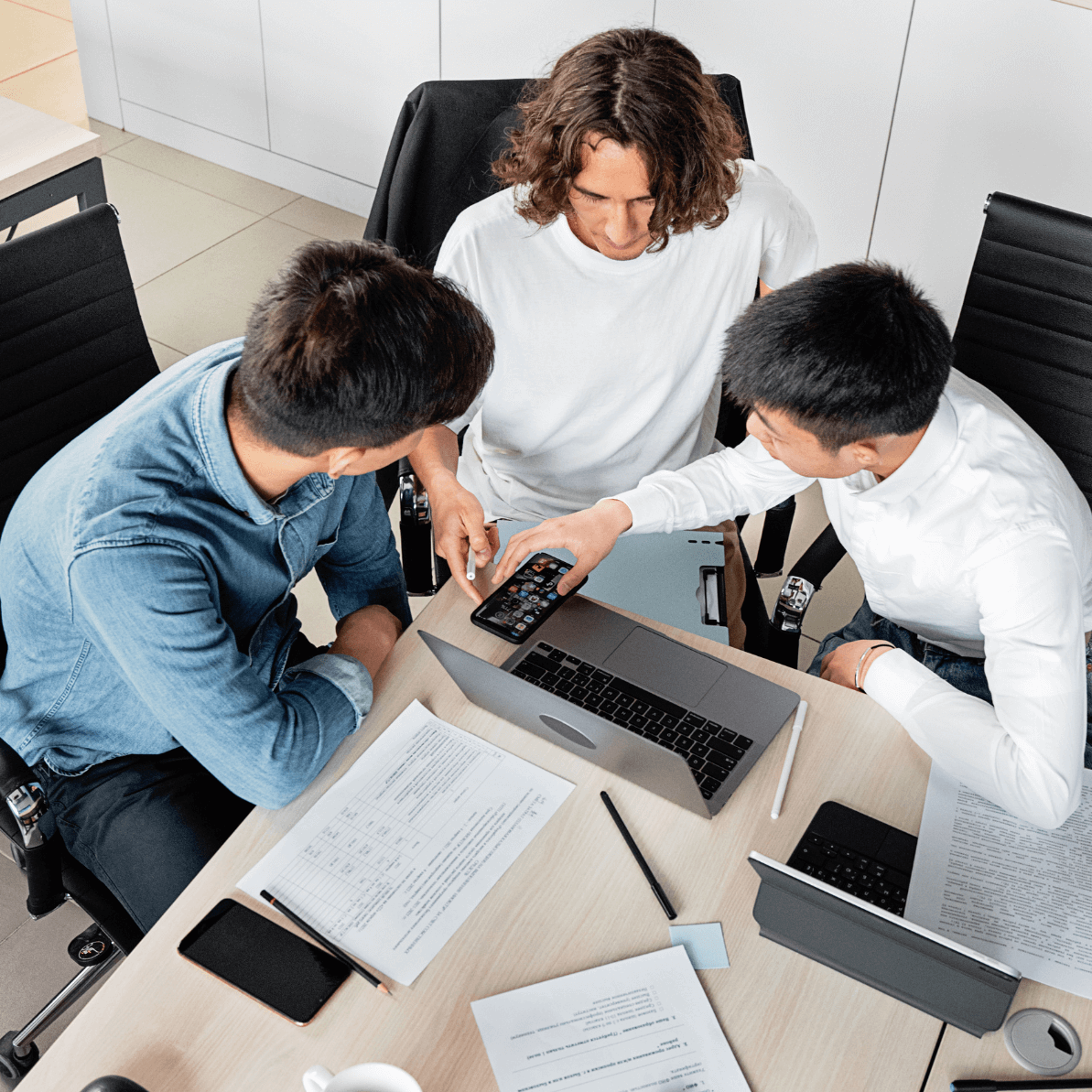 Team collaborating around a laptop at a desk